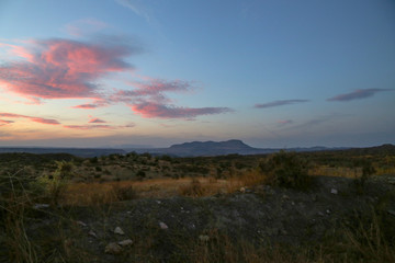 Naklejka na ściany i meble sunset over a mountain with purple red clouds and a blue sky at a grassland landscape