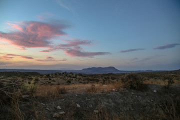 Naklejka na ściany i meble sunset over the mountains with clear blue sky and purple clouds over a steppe grassland