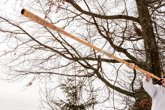 An old grandfather in vyshivanka plays trembita in the Carpathian mountains in winter