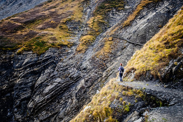 Young woman hiking a narrow trail in the Alps of Oisans
