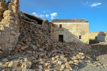 Old ruins of farm houses with a pile of stones under sunny blue sky
