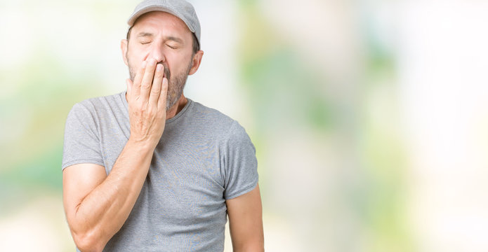 Handsome middle age hoary senior man wearing sport cap over isolated background bored yawning tired covering mouth with hand. Restless and sleepiness.