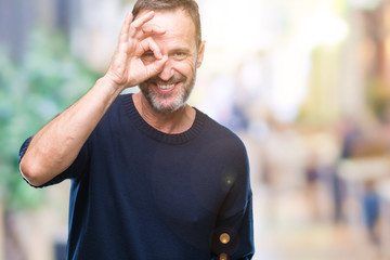 Middle age hoary senior man over isolated background doing ok gesture with hand smiling, eye looking through fingers with happy face.