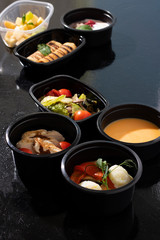 ready meal to eat in food containers, asian dishes on black table