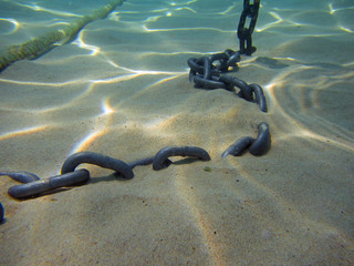 Seabed with sand and anchor chain, close up