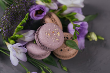 Obraz na płótnie Canvas Heap of sweet french macarons mixed with flowers on grey concrete background