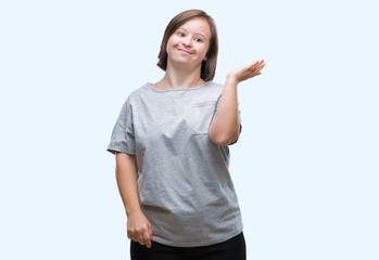 Young adult woman with down syndrome over isolated background smiling cheerful presenting and pointing with palm of hand looking at the camera.