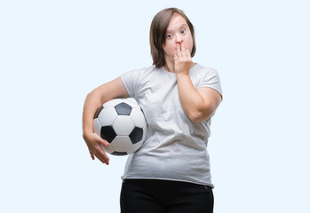 Young adult woman with down syndrome holding soccer football ball over isolated background cover mouth with hand shocked with shame for mistake, expression of fear, scared in silence, secret concept