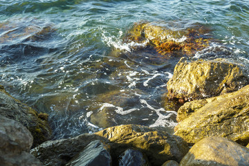 The wreckage of rocks in the sea near the rocky shore in the sea foam.