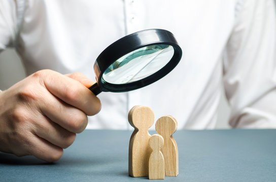 A man looks through a magnifying glass at a family figure. The study of family composition and demographic situation. Statistical data. The program of support for young families, financial assistance.