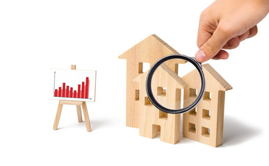 Magnifying glass is looking at the wooden houses with a stand of graphics and information. Growing...