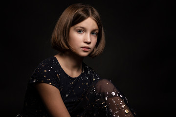 Beautiful sad teen girl, close-up portrait, black background