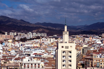 View of the Spanish city of Malaga from a height. Residential buildings, mountains, sights on the background of a cloudy sky.