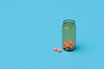Orange pills, tablets and brown glass bottle on blue background. Copy space for text