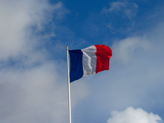 Fabric textile tricolor flag of France flying in the high wind