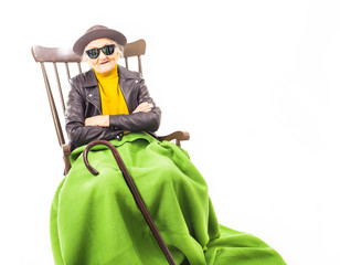 Old woman with sunglasses sitting on a chair.