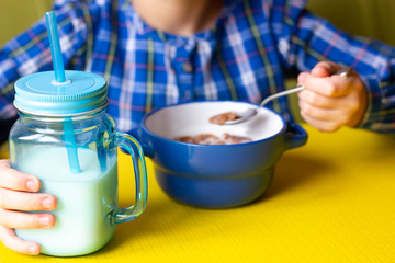 Happy child eats cereals with milk.