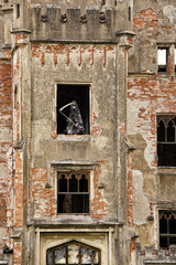 Broken facade of the old castle with statue of death