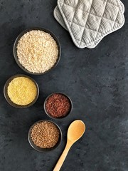 Red rice, buckwheat, millet and oatmeal on dark background