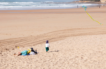Fototapeta na wymiar child flying a kite on the beach