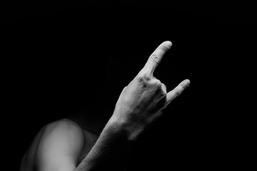 Male hand close-up on a black background shows hand gesture. Rock'n'roll.