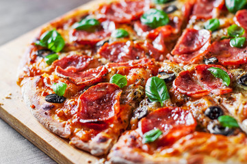 Pepperoni Pizza with Mozzarella cheese, salami, Tomatoes, olive, pepper, Spices and Fresh Basil. Italian pizza on wooden table background