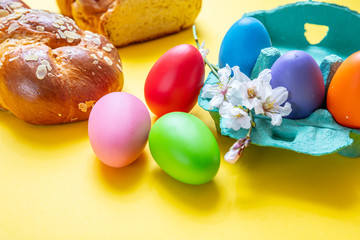 Obraz na płótnie Canvas Easter eggs and tsoureki braid, greek easter sweet bread, on yellow background
