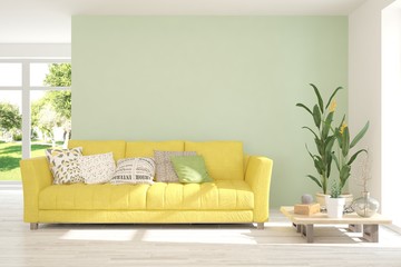 Green stylish minimalist room with sofa and summer landscape in window. Scandinavian interior design. 3D illustration