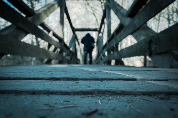 Mann geht über eine Holzbrücke