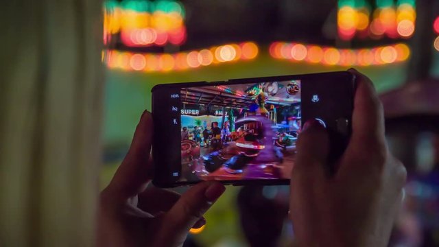 A woman is recording children when they are riding on a roundabout