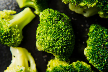 Broccoli on a black plate. Black background, side view, close-up