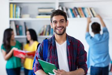 Lachender spanischer Student in der Uni-Bibliothek 