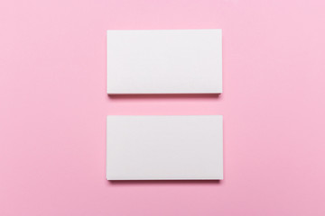 Blank white business cards on pink background.