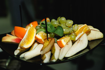 Фруктовая тарелка с виноградом, апельсином, грушей и яблоком декорированная листьями мяты