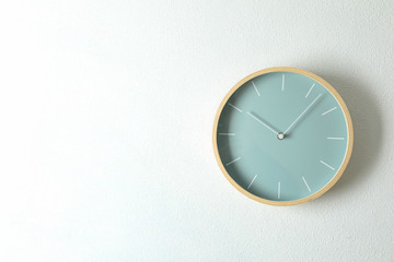 Big beautiful stylish clock hanging on light background, space for text
