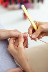 Professional manicurist cleaning cuticle from behind a nail