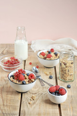 Granola with berries, with milk and cutlery. The concept of a healthy breakfast. Light wooden background. Vertical frame orientation. 