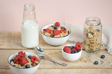 Granola with berries, with milk and cutlery. The concept of a healthy breakfast. Light wooden background.  Close-up.