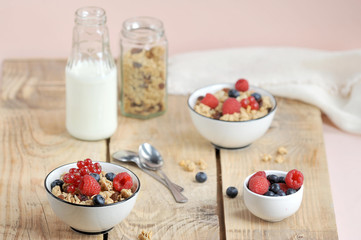 Granola with berries, with milk and cutlery. The concept of a healthy breakfast. Light wooden background.  Close-up.