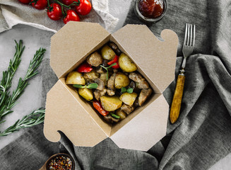 Baked potatoes with meat and vegetables in a cardboard box in a beautiful serving