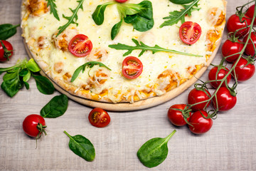 top view of pizza with tomatoes and herbs over wooden table