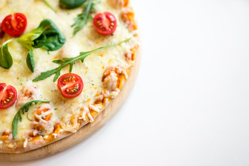 close up top view of pizza with tomatoes and herbs and copy space over white