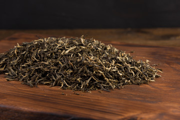 dry green tea isolated on the wooden table on black background
