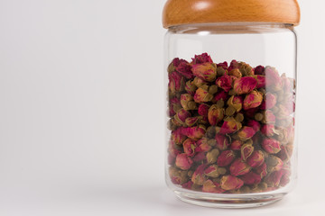 tea rose buds in the transparent jar isolated on white background