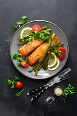 Grilled salmon fish steak, asparagus, tomato and corn salad on plate. Healthy dish for lunch. Top view