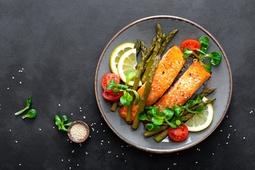 Grilled salmon fish steak, asparagus, tomato and corn salad on plate. Healthy dish for lunch. Top...