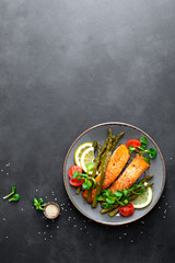Grilled salmon fish steak, asparagus, tomato and corn salad on plate. Healthy dish for lunch. Top view