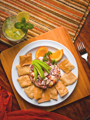 Fish ceviche with avocado, tortilla chips and a mojito