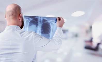 Naklejka na ściany i meble Young male doctor examining x-ray on white