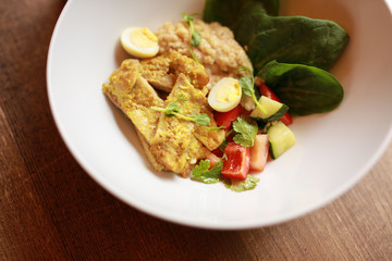 Chicken curry with salad in the plate on a wooden table